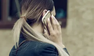 Kobieta rozmawia przez telefon, martwiąc się, czy pracodawca może odmówić urlopu na żądanie.