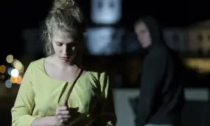 Przerażona kobieta w żółtej bluzce czuje się obserwowana. Kto to? Czy to stalker?
