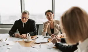 Biznesmeni przy stole analizują dokumenty. Dyskusja dotyczy prawa pierwokupu.