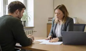 Rozmowa o tym, czy z wyrokiem można pracować w urzędzie. Kobieta w garniturze i mężczyzna siedzą przy biurku.