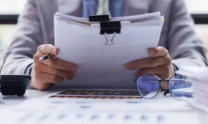 Biznesmen analizuje dokumenty, zastanawiając się nad strategią b2b. Co to znaczy? To relacje między firmami.