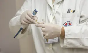 Laborant w białym fartuchu, w rękawiczkach, pobiera próbkę do analizy. To część procesu, który może pomóc odpowiedzieć na pytanie: obdukcja co to.