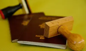 Stempel nad paszportem, symbolizujący biurokrację i potencjalną deportację.