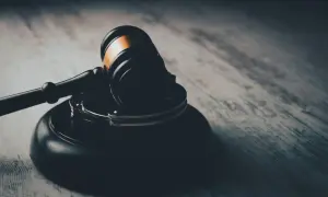 Młotek sędziowski i kajdanki na drewnianym tle.