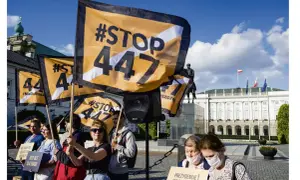 Protestujący trzymają flagi z napisem #STOP 447, sprzeciwiając się ustawie 447. W tle Pałac Prezydencki.
