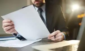 Adwokat z własną kancelarią analizuje dokumenty, zastanawiając się, ile zarabia.