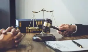 Sądowy młotek w dłoni prawnika, waga sprawiedliwości i księgi. Czy wyrok nieprawomocny obowiązuje?