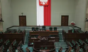 Pusta sala sejmowa, gotowa na głosowanie weta prezydenta. Biało-czerwona flaga i godło Polski na ścianie.