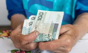 Dłonie trzymają polskie banknoty 100 zł i 10 zł. Pytanie: umowa zlecenie - ile na godzinę netto?
