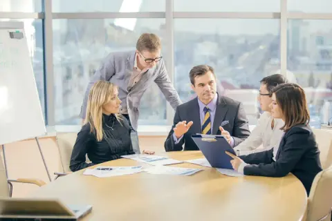 Zespół biznesowy przy stole dyskutuje, jeden mężczyzna gestykuluje.