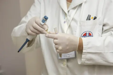 Laborant w białym fartuchu, w rękawiczkach, pobiera próbkę do analizy. To część procesu, który może pomóc odpowiedzieć na pytanie: obdukcja co to.