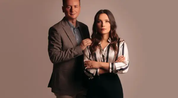 Mężczyzna w garniturze i kobieta w bluzce w paski stoją obok siebie.