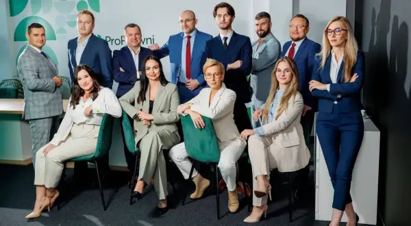 Grupa profesjonalistów w garniturach pozuje do zdjęcia w nowoczesnym biurze.
