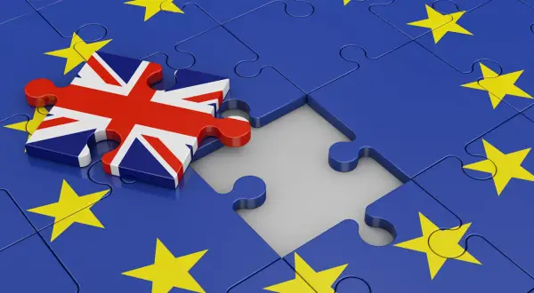 Fragment układanki z flagą Wielkiej Brytanii obok Unii Europejskiej. Symbolizuje Brexit, a w szerszym kontekście może nawiązywać do trudności w relacjach międzynarodowych, jak ekstradycja co to.