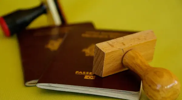 Stempel nad paszportem, symbolizujący biurokrację i potencjalną deportację.
