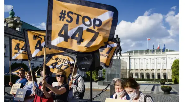 Protestujący trzymają flagi z napisem #STOP 447, sprzeciwiając się ustawie 447. W tle Pałac Prezydencki.