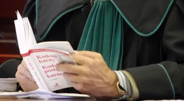 Prawnik w todze czyta Kodeks karny.