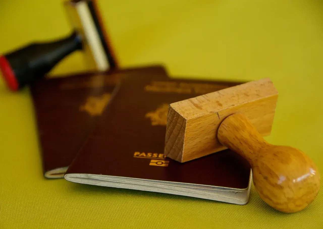 Stempel nad paszportem, symbolizujący biurokrację i potencjalną deportację.