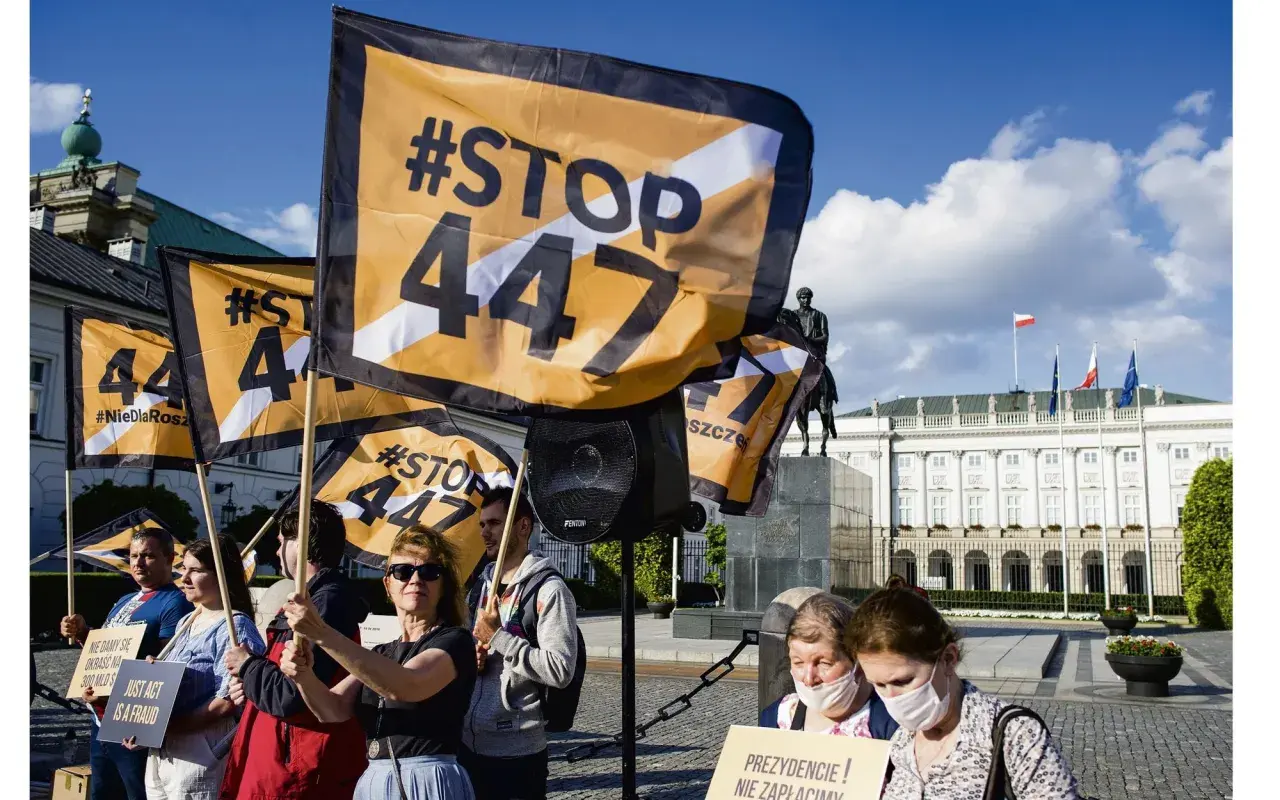 Protestujący trzymają flagi z napisem #STOP 447, sprzeciwiając się ustawie 447. W tle Pałac Prezydencki.