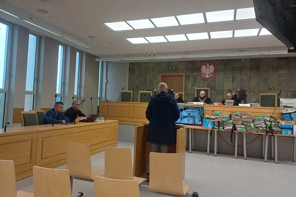 Oskarżony może zobaczyć zeznania świadków na ekranie. Sąd, ława przysięgłych i stosy akt w sali sądowej.