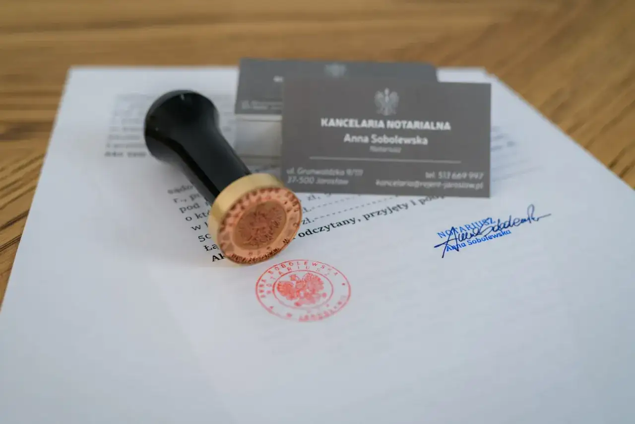 Pieczęć i wizytówka Anny Sobolewskiej, rejenta, leżą na dokumencie.